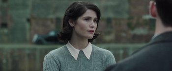 Movie still from “Their Finest” (2016), directed by Lone Scherfig – A woman in a grey sweater looking to her left; Close Up shot, Over the shoulder angle