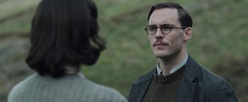 Movie still from “Their Finest” (2016), directed by Lone Scherfig – A man with a beard and glasses talking to a woman; Close Up shot, Over the shoulder angle
