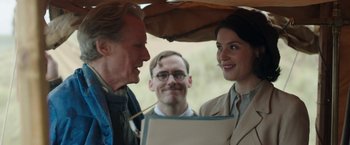 Movie still from “Their Finest” (2016), directed by Lone Scherfig – A man and a woman standing under an umbrella; Medium shot, Over the shoulder angle