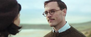 Movie still from “Their Finest” (2016), directed by Lone Scherfig – A person wearing glasses and a sweater; Close Up shot, Low angle
