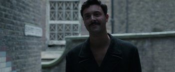 Movie still from “Their Finest” (2016), directed by Lone Scherfig – A man with a beard and mustache wearing a black shirt; Close Up shot, Low angle