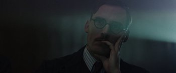 Movie still from “Their Finest” (2016), directed by Lone Scherfig – A man in a suit and tie holding a cell phone to his ear; Close Up shot, Low angle