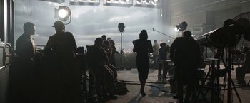 Movie still from “Their Finest” (2016), directed by Lone Scherfig – A group of people are sitting in a room; Wide shot, Over the shoulder angle