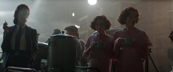 Movie still from “Their Finest” (2016), directed by Lone Scherfig – A woman holding a coffee cup in a room; Medium shot, Over the shoulder angle