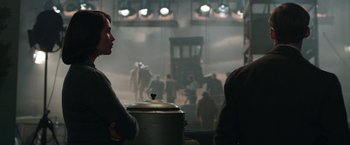 Movie still from “Their Finest” (2016), directed by Lone Scherfig – Two people standing next to each other in front of a train; Medium shot, Over the shoulder angle