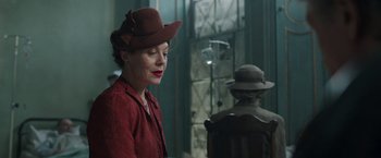 Movie still from “Their Finest” (2016), directed by Lone Scherfig – A woman wearing a hat and a red jacket; Medium shot, Over the shoulder angle