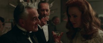 Movie still from “Their Finest” (2016), directed by Lone Scherfig – A group of people standing next to each other holding wine glasses; Close Up shot, Over the shoulder angle