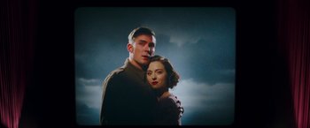 Movie still from “Their Finest” (2016), directed by Lone Scherfig – A man and a woman standing next to each other in front of a cloudy sky; Medium shot, Low angle