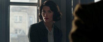 Movie still from “Their Finest” (2016), directed by Lone Scherfig – A woman in a suit looking at the camera; Close Up shot, Over the shoulder angle