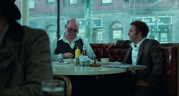 Movie still from “Thief” (1981), directed by Michael Mann – Two men sitting at a table in front of a window; Medium shot, Over the shoulder angle