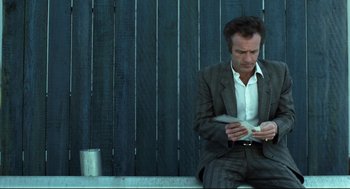 Movie still from “Thief” (1981), directed by Michael Mann – A man sitting on a bench looking at his cell phone; Medium shot, Low angle