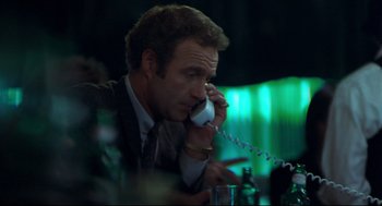Movie still from “Thief” (1981), directed by Michael Mann – A man sitting at a table talking on a phone; Close Up shot, Low angle