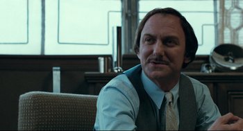 Movie still from “Thief” (1981), directed by Michael Mann – A person sitting in a chair wearing a tie; Close Up shot, Over the shoulder angle