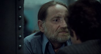 Movie still from “Thief” (1981), directed by Michael Mann – An older man with long hair and a long beard; Close Up shot, Over the shoulder angle