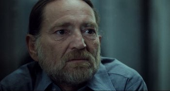 Movie still from “Thief” (1981), directed by Michael Mann – An old man with a beard and a blue shirt; Close Up shot, Over the shoulder angle