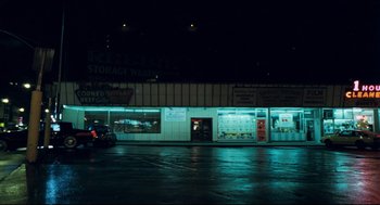 Movie still from “Thief” (1981), directed by Michael Mann – A car parked on the side of the road in front of a store; Extreme Wide shot, High angle