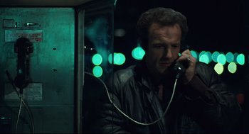 Movie still from “Thief” (1981), directed by Michael Mann – A man talking on a phone in front of a window; Close Up shot, Low angle