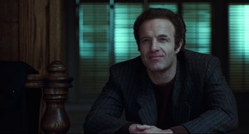 Movie still from “Thief” (1981), directed by Michael Mann – A man in a suit sitting in front of a wooden post; Medium shot, Low angle