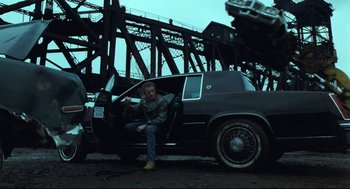 Movie still from “Thief” (1981), directed by Michael Mann – A man sitting in the driver's seat of a black car; Wide shot, Low angle