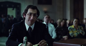 Movie still from “Thief” (1981), directed by Michael Mann – A man sitting at a table in front of a microphone; Close Up shot, Low angle