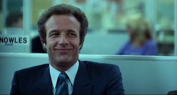 Movie still from “Thief” (1981), directed by Michael Mann – A man wearing a suit and tie smiling for the camera; Close Up shot, Low angle