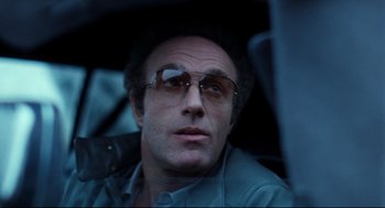 Movie still from “Thief” (1981), directed by Michael Mann – A person wearing glasses in a car; Close Up shot, Low angle