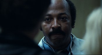 Movie still from “Thief” (1981), directed by Michael Mann – A man wearing a stethoscope looking into the camera; Close Up shot, Over the shoulder angle