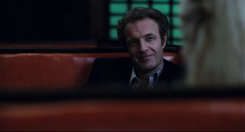 Movie still from “Thief” (1981), directed by Michael Mann – A man in a suit and tie sitting in a booth; Close Up shot, Over the shoulder angle