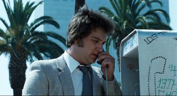 Movie still from “Thief” (1981), directed by Michael Mann – A man wearing a suit and tie talking on a cell phone; Close Up shot, Low angle