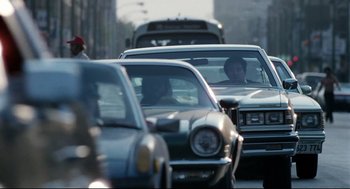 Movie still from “Thief” (1981), directed by Michael Mann – A group of cars driving down a street with traffic; Wide shot, Over the shoulder angle