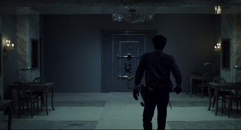 Movie still from “Thief” (1981), directed by Michael Mann – A man holding a knife in front of an open door; Wide shot, Low angle