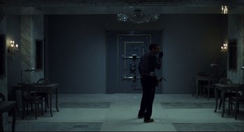 Movie still from “Thief” (1981), directed by Michael Mann – A man standing in front of an open door in a dark room; Wide shot, Low angle