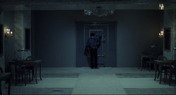 Movie still from “Thief” (1981), directed by Michael Mann – A man standing in front of an open door; Wide shot, High angle