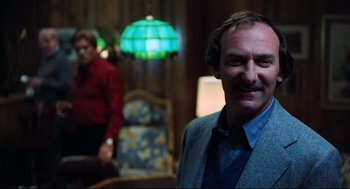 Movie still from “Thief” (1981), directed by Michael Mann – A man standing in front of another man in a room; Medium shot, Over the shoulder angle