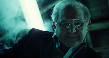 Movie still from “Thief” (1981), directed by Michael Mann – An old man with glasses sitting in a chair; Close Up shot, Over the shoulder angle