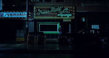 Movie still from “Thief” (1981), directed by Michael Mann – A man standing in front of a green mill cocktail lounge; Extreme Wide shot, Low angle