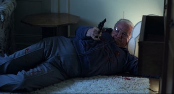 Movie still from “Thief” (1981), directed by Michael Mann – A man laying on the ground holding a gun; Medium shot, High angle