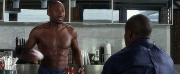 Movie still from “Think Like a Man” (2012), directed by Tim Story – A shirtless man is standing in front of another man in a kitchen; Medium shot, Over the shoulder angle
