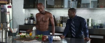 Movie still from “Think Like a Man” (2012), directed by Tim Story – A man standing next to another man in a kitchen; Medium shot, Over the shoulder angle