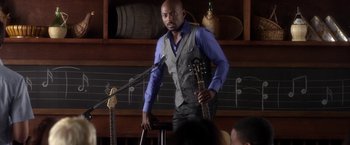 Movie still from “Think Like a Man” (2012), directed by Tim Story – A man holding a microphone and a guitar; Medium shot, Over the shoulder angle