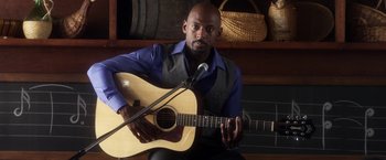 Movie still from “Think Like a Man” (2012), directed by Tim Story – A man holding a microphone and a guitar; Medium shot, Over the shoulder angle
