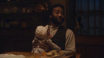 Movie still from “Anne with an E” (2017), created by Moira Walley-Beckett – A man holding a baby in his arms in a kitchen; Medium shot, Over the shoulder angle