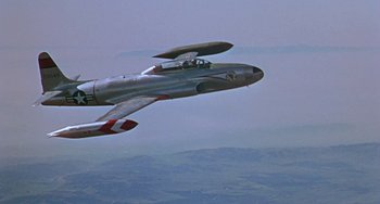 Movie still from “This Island Earth” (1955), directed by Joseph M. Newman – An airplane is flying in the air with a sky background; Wide shot, High angle
