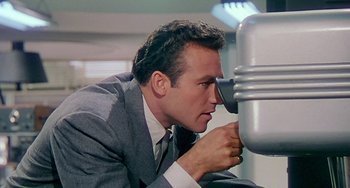 Movie still from “This Island Earth” (1955), directed by Joseph M. Newman – A man in a suit looking through a telescope; Close Up shot, Low angle