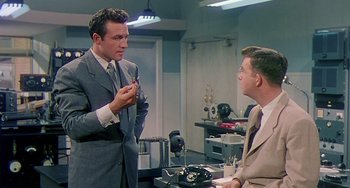 Movie still from “This Island Earth” (1955), directed by Joseph M. Newman – A man in a gray suit talking to another man in a gray suit; Medium shot, Over the shoulder angle