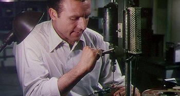 Movie still from “This Island Earth” (1955), directed by Joseph M. Newman – A man working on a machine in a shop; Close Up shot, Low angle