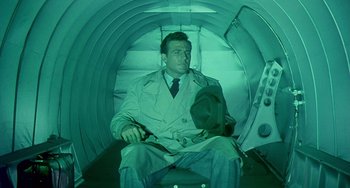 Movie still from “This Island Earth” (1955), directed by Joseph M. Newman – A man sitting in a tunnel with a hat on; Medium shot, High angle