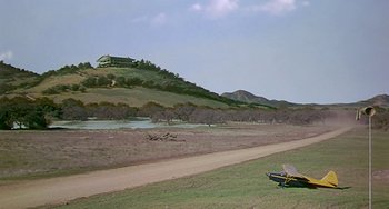 Movie still from “This Island Earth” (1955), directed by Joseph M. Newman – An airplane sitting on top of a grass covered field; Extreme Wide shot, Low angle