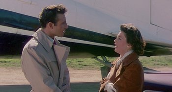 Movie still from “This Island Earth” (1955), directed by Joseph M. Newman – A man and a woman standing next to each other near an airplane; Medium shot, Over the shoulder angle