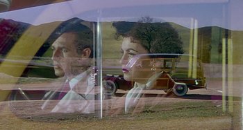 Movie still from “This Island Earth” (1955), directed by Joseph M. Newman – A man and a woman in front of an antique car; Wide shot, Low angle